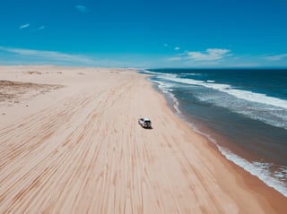 Ein Geländewagen am Strand mit Wellen