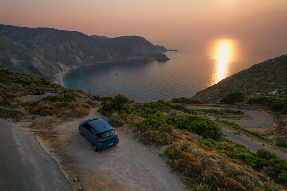 Ein geparktes Auto an einer Bucht bei Sonnenuntergang in Griechenland.