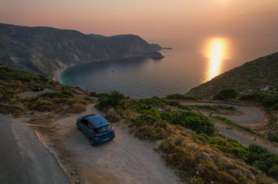 Ein geparktes Auto an einer Bucht bei Sonnenuntergang in Griechenland.