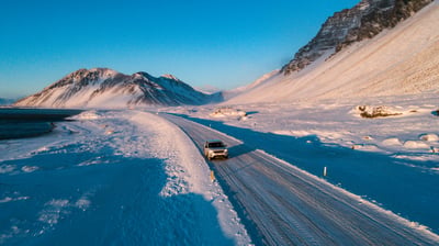 Verschneite Landschaft mit einem 4x4 auf einer Straße in Island